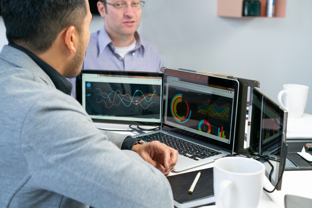Person using a laptop with two extended screens on either side of the monitor