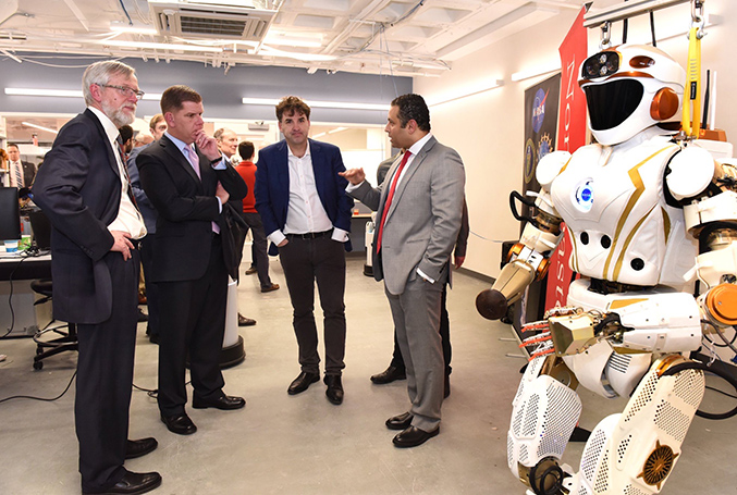 Fady Saad speaks with a group of men next to a humanoid robot