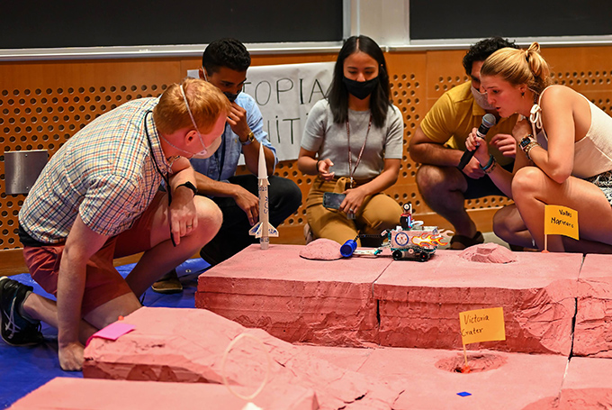 Students gather around a Lego rover, which is navigating a model of the Martian landscape