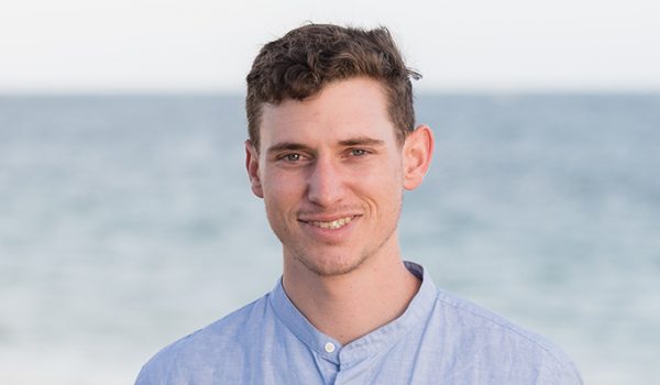 Portrait of Daniel Anastos standing in front of the ocean