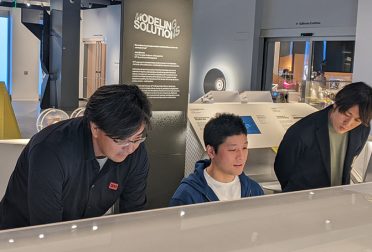 Three men interact with a museum exhibit.