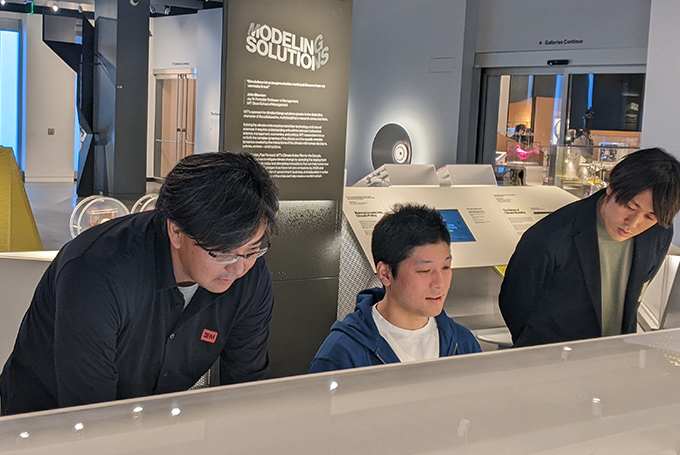 Three men interact with a museum exhibit.