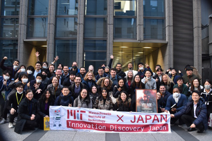Students and staff gathered in front of an office building holding a banner reading "MIT x Japan Innovation Discovery Japan"