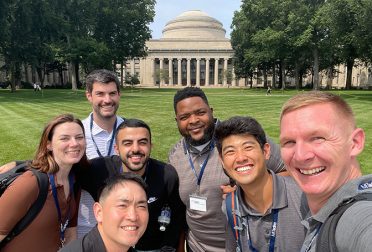 A group of students smiling in front of the MIT Dome.