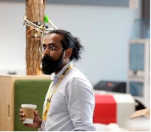 A man with a ponytail and beard, holding a cup of coffee. 