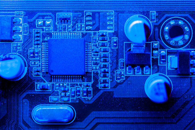 A close-up of a motherboard's circuitry, tinted a deep blue.