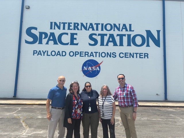 Five people stand in front of the International Space Station Payload Operations Center