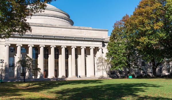 MIT's iconic dome, with trees showing the start of their autumn colors beside it.
