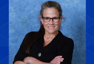 A headshot of Christine Miyachi, arms folded and giving a confident smile to the camera.