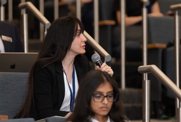 A student in a lecture hall speaks on a microphone.
