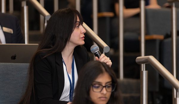 A student in a lecture hall speaks on a microphone.