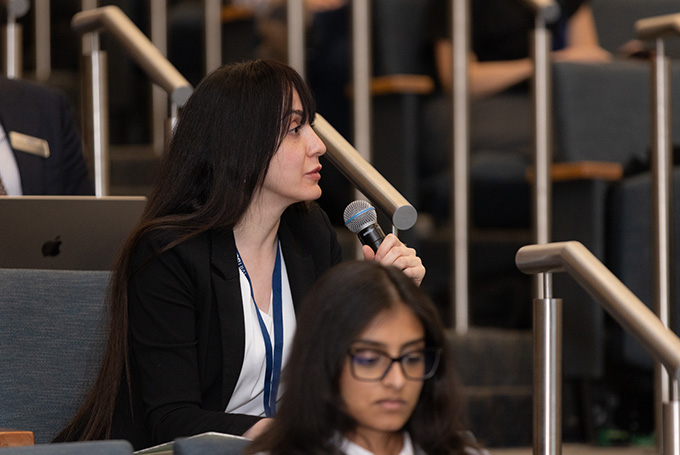 A student in a lecture hall speaks on a microphone.