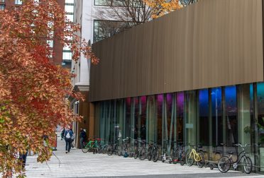 The MIT Welcome Center, with a tree with orange fall foliage in the foreground.
