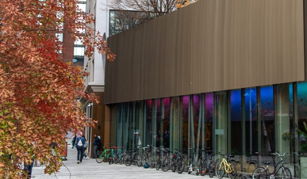 The MIT Welcome Center, with a tree with orange fall foliage in the foreground.