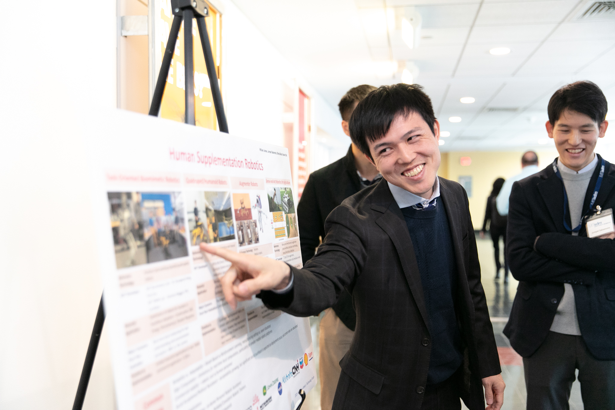 A smiling student points something out on a scientific poster.